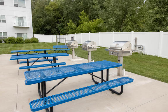 a row of blue picnic tables in front of three grilling machines