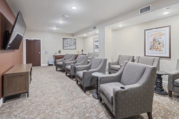 a waiting room filled with chairs and a television at The Winslow 62+ Apartments, West St Paul, MN
