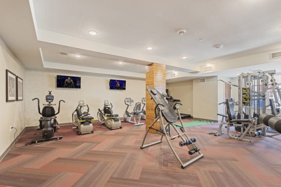 a gym with weights and machines on a wooden floor at The Winslow 62+ Apartments, Minnesota