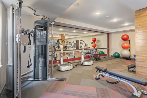 a gym with cardio equipment and weights on the floor at The Winslow 62+ Apartments, West St Paul, Minnesota