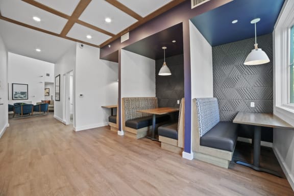 a seating area with tables and chairs in the center of a room with a blue accent wall