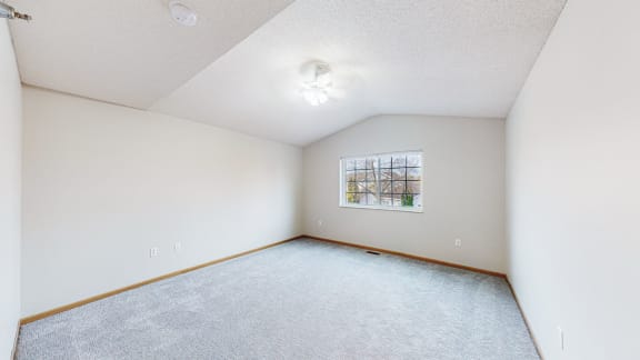 a spacious living room with carpet and a window