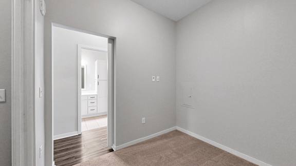 A room with white walls and a doorway leading to another room.