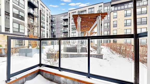 A balcony with a view of a snowy landscape and apartment buildings.
