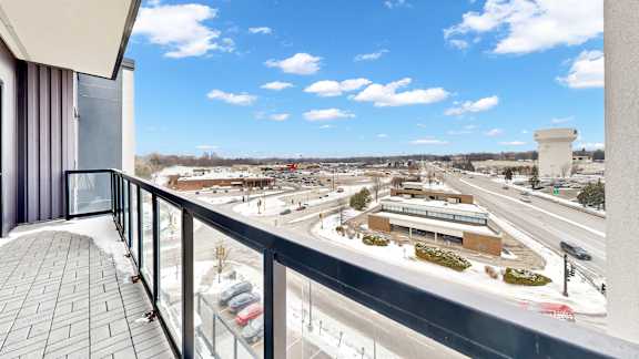A balcony overlooks a busy highway and a parking lot.