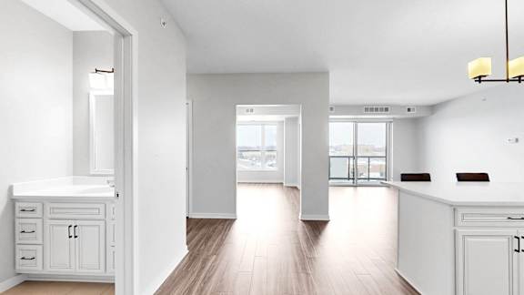 A white kitchen with a large island and a view of the city.