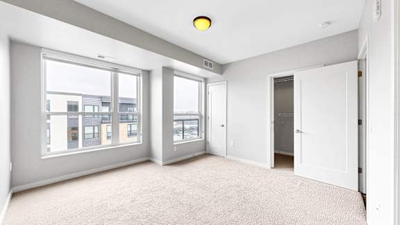 A spacious room with large windows and a carpeted floor.