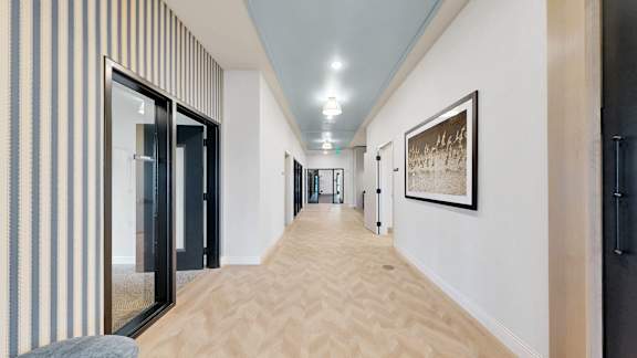 A long hallway with a striped wall on the left and a picture on the right.