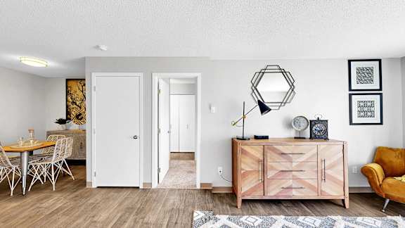 A room with a wooden floor and a white wall with a framed picture on it.