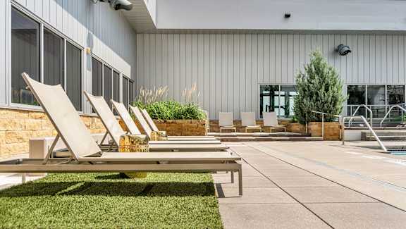 A poolside area with lounge chairs and a building in the background. at Custom House, Saint Paul, Minnesota
