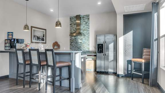 A kitchen with a bar area and a refrigerator with a glass door.