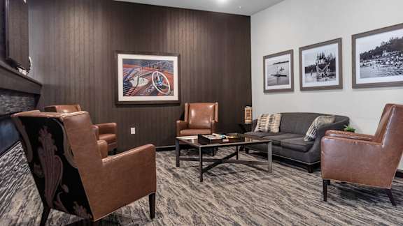 A living room with brown leather chairs and a grey couch.