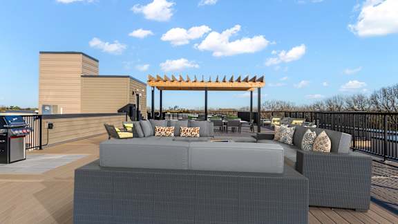 A modern outdoor seating area with grey couches and a wooden pergola.