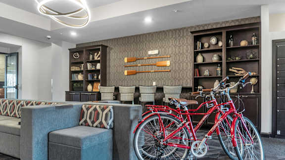 A red bicycle is parked in front of a wall with shelves and decorative items.