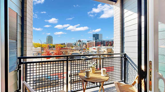 A balcony with a table and chairs overlooking a cityscape.