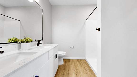 A white bathroom with a wooden floor and a white toilet.