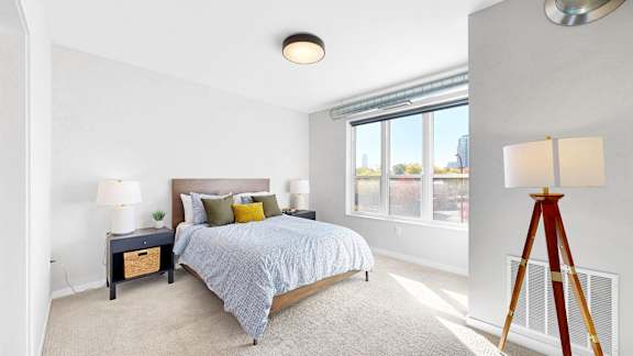 A bedroom with a bed, nightstand, and window.