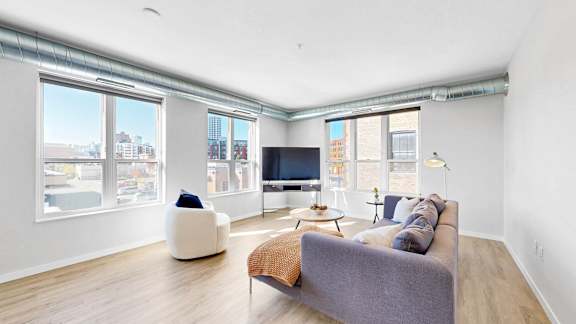 A living room with a grey couch, a white chair, and a television.