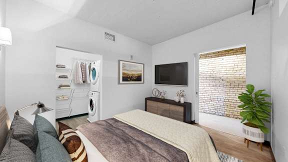 A bedroom with a bed, a washing machine, and a plant.