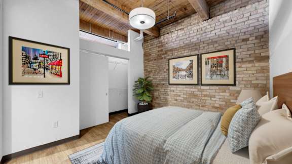 A bedroom with a bed, a plant, and pictures on the wall.