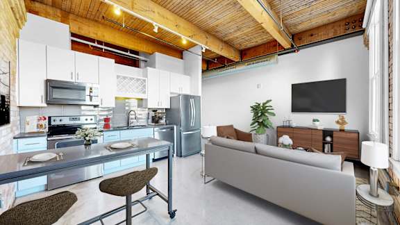 A modern kitchen with a breakfast bar and a living room area with a couch and a TV.