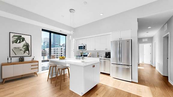 A modern kitchen with a white island and stainless steel appliances.