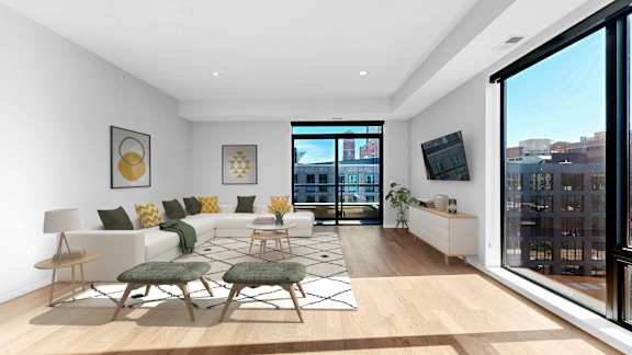 A living room with a white couch, a green chair, and a wooden floor.