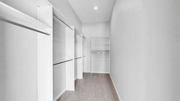 A long hallway with white walls and a grey carpet.