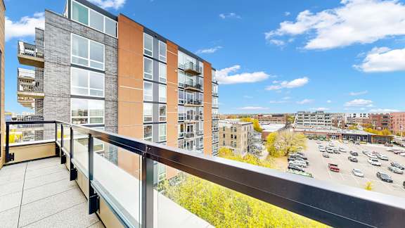 A balcony overlooks a parking lot and buildings.