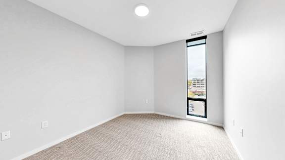A white room with a window and a poster on the wall.