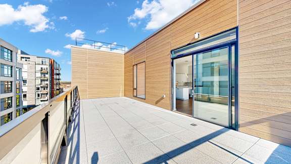 A modern balcony with a glass door and a wooden wall.