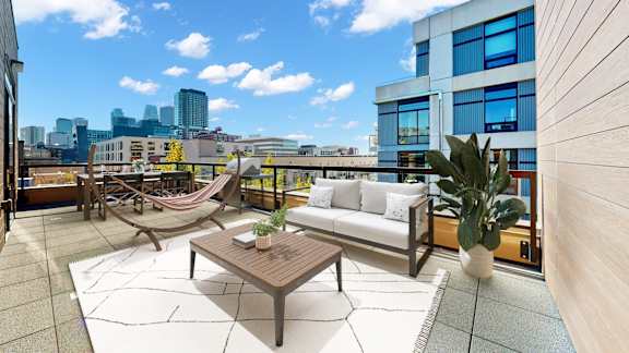 A modern balcony with a hammock, a couch, and a coffee table.