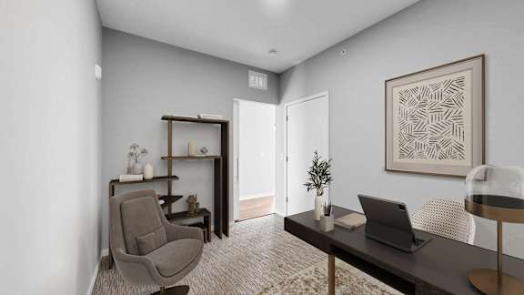 A room with a chair, a table, and a laptop.