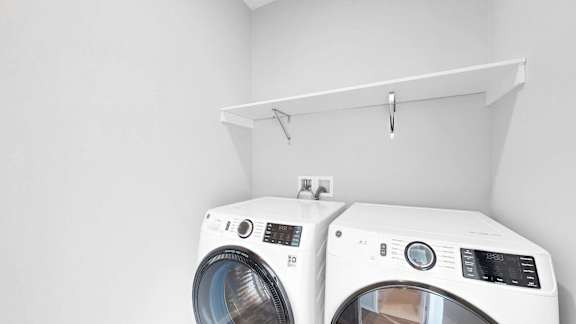 Two white front load washing machines in a laundry room.
