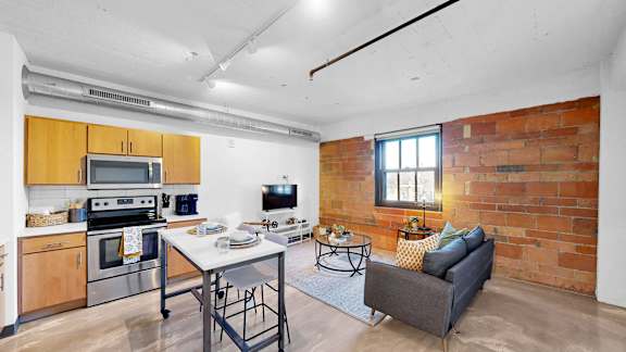 A kitchen with a table and chairs in front of a brick wall.