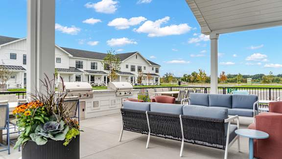 A patio with a sofa and chairs overlooking a white building.
