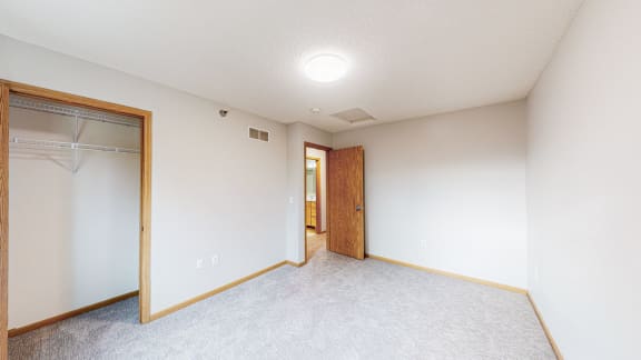 an empty room with a closet and a door to a bathroom