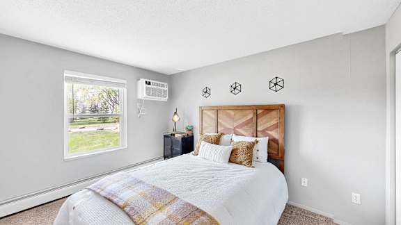 A bedroom with a large bed and a window overlooking a green lawn.