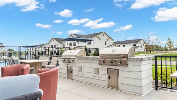 A white outdoor kitchen with a grill and seating area.