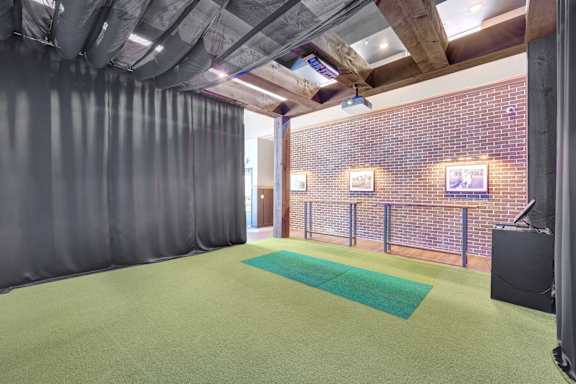 A room with a green carpet and a brick wall.