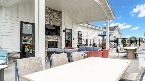 A white building with a stone fireplace and a white table and chairs outside.
