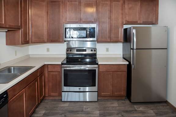 A kitchen with brown cabinets and stainless steel appliances.