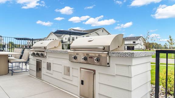 A white outdoor kitchen with a grill and sink.