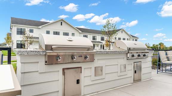 A white outdoor kitchen with a grill and sink.