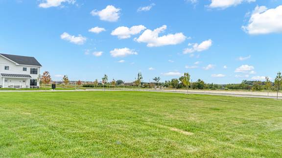 A large grassy field with a house in the background.