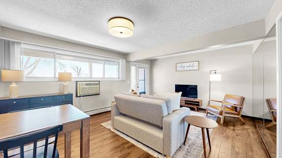 A living room with a grey couch, a wooden table, and a television.