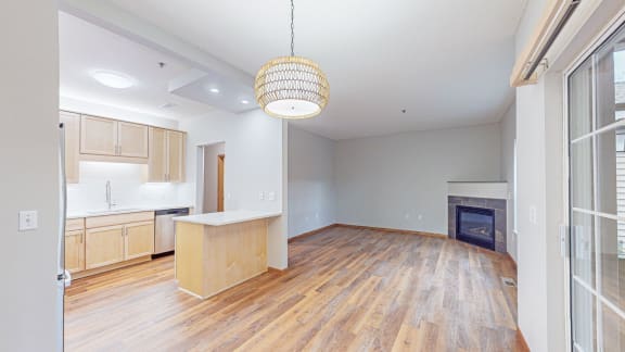an empty living room with a kitchen and a fireplace