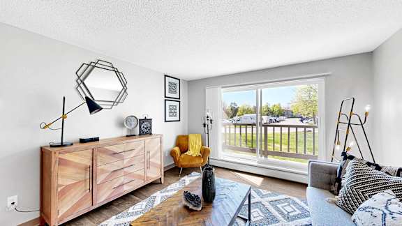 A living room with a yellow chair and a wooden cabinet.