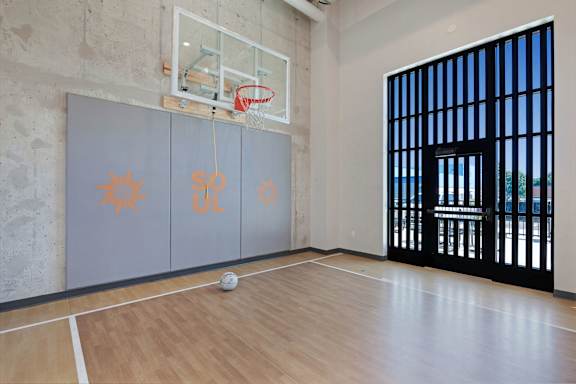 A basketball court with a ball on the floor and a basketball hoop with a net at Soul Apartments, St. Paul, 55107