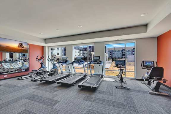 A gym with treadmills, exercise bikes, and a television at Lochner Apartments, MN, 55110